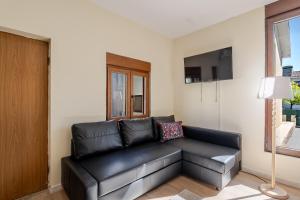 a black leather couch in a living room with a tv at Maia Oporto Suites in Maia