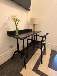 a table with a vase of flowers and a chair at Dimora di Duen - Villa Storica di Charme in Villa San Giovanni