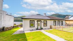 a small white house with a grass yard at Cottage on the Loch in Arrochar