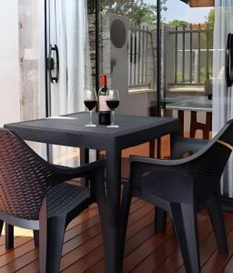 a black table and two glasses of wine on a balcony at Studio Hebron: Refúgio Entre a Cidade e a Natureza in Anápolis