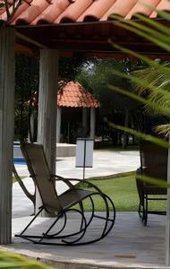two chairs sitting on a porch with an umbrella at Studio Hebron: Refúgio Entre a Cidade e a Natureza in Anápolis