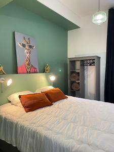 a bedroom with a white bed with a painting on the wall at Le balcon du Beffroi in Fougères