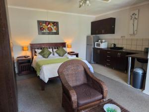 a bedroom with a bed and a chair and a kitchen at Sekelbos Guesthouse in Pretoria