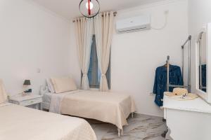 a white room with two beds and a window at Villa Leta in Kokkari