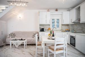 a kitchen and living room with white cabinets and a table at Villa Leta in Kokkari
