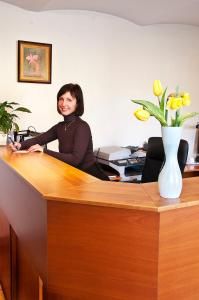 een vrouw aan een bureau met een vaas vol bloemen bij Linovo with FREE Parking in Rīga