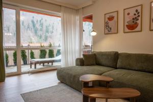 a living room with a couch and a large window at Forestline Apartment Sinaia in Sinaia