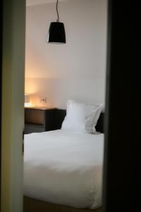 a bedroom with a white bed and a lamp at Les Appartements du Vignoble in Kientzheim
