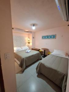 a hotel room with two beds and a table at Sabatico Beach House in Búzios