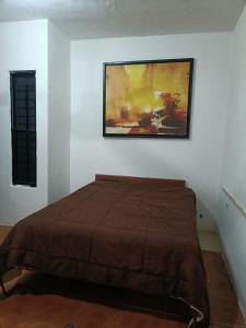 a bed in a room with a painting on the wall at Casa Albino in Izamal