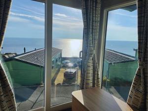 a room with a large window looking out at the ocean at Hendre Coed Isaf Caravan Park in Barmouth