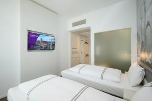 two beds in a room with a tv on the wall at Premier Inn München City West in Munich