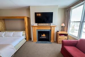 a bedroom with a bed and a fireplace with a tv at Long Trail House 459 in Stratton