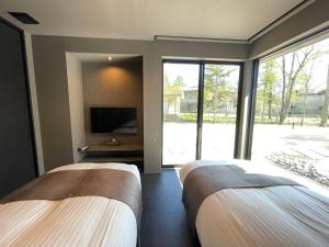 two beds in a room with a large window at Fuji Yamanakako Villa in Yamanakako