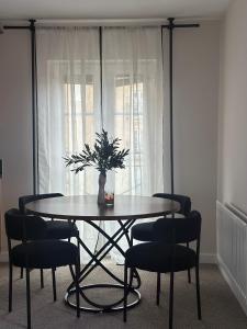 a dining room table with chairs and a vase with a plant at Modern 2 bed flat with parking by Bluewater shopping mall in Greenhithe