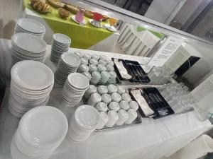 a counter with white cups and plates on a table at Hotel Pampulha Palace in Belo Horizonte
