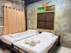 two beds in a room with a window at Belvilla Baan Elephant Home in Chiang Mai