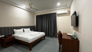 a bedroom with a bed and a desk and a television at Rangoli Suites & Restrobar in Bantvāl