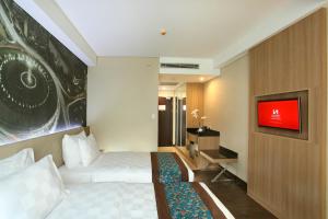 a hotel room with a bed and a tv at Swiss-Belhotel Airport Jakarta in Tangerang