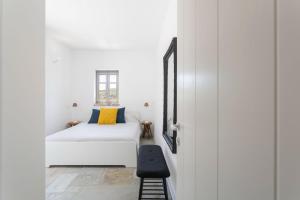 a small bedroom with a white bed and a black stool at Oxalis Villas in Perlengiánika