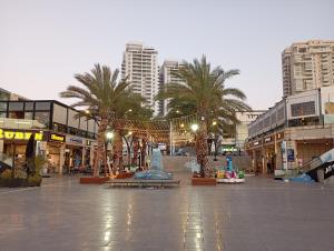 a shopping center with palm trees and buildings at Marina Breeze in Ashkelon