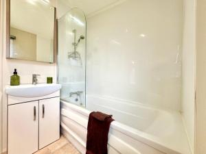 a white bathroom with a sink and a tub at Oaklands Holiday Park in Saint Osyth +15 photos