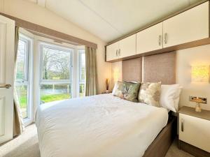 a bedroom with a large bed and a window at Oaklands Holiday Park in Saint Osyth