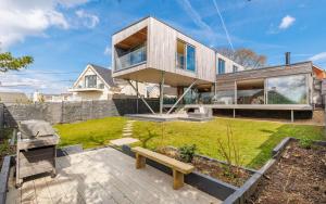 a house with a bench in the yard at Rena's Retreat - Luxury Architectural Eco Home with hot tub a short walk from Gurnard in Cowes - Perfect Lux Stay for Sailers Couples and Older Families in Gurnard