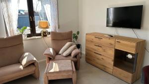 a living room with a tv and a chair and a dresser at Ferienwohnung Wirtz in Olzheim