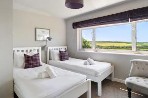 two beds in a room with a window and a chair at 2 Bed in St. Brides oc-s30491 in Saint Brides