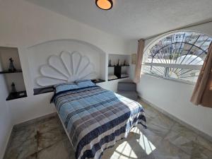 a bedroom with a bed and a large window at Casa Secretos del Sol in Acapulco