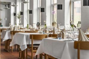 ein Restaurant mit Tischen und Stühlen mit weißen Tischdecken in der Unterkunft Hotel Fuglsocentret, BW Signature Collection in Knebel