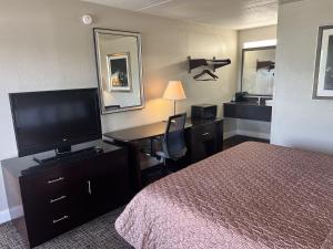 a hotel room with a bed and a desk with a television at UNIVERSITY INN Winston in Winston-Salem