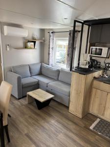 a living room with a couch and a table at Mobil Home 6 personnes camping 4 etoiles Bonne Anse la Palmyre in Les Mathes