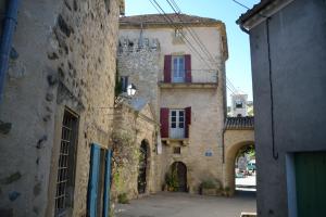 an old stone building with red windows and an alley at Château de Rosans in Rosans