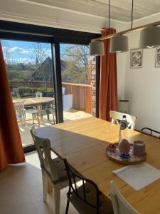 a dining room with a large wooden table with chairs at La maison d'à côté - Sart in Jalhay