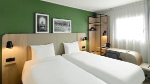 a hotel room with two beds and a green wall at Campanile PRIME - Nogent-sur-Marne in Nogent-sur-Marne