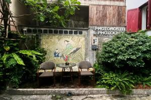 two chairs and a table in front of a wall at Photohostel in Bangkok