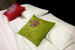 a green pillow with a flower on a bed at Photohostel in Bangkok +16 photos
