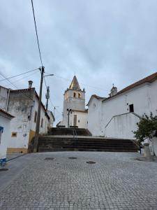 a building with a clock tower in the middle of a street at Casa da Ana - Casinhas com Alma in Torrão