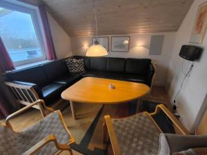 ein Wohnzimmer mit schwarzem Sofa und Holztisch in der Unterkunft Læsø Efterskole in Læsø