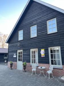 two chairs and a table in front of a building at B&B Aan t End in Kootwijkerbroek