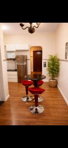a kitchen with a table and four red chairs at Edifício Marília in Marília