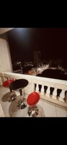 a table and two red chairs on a balcony with a view at Edifício Marília in Marília