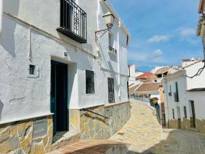 an alley with a white building and a blue door at La casa del pinsapo in Yunquera