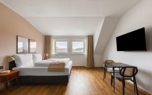 a bedroom with a bed and a table and a tv at Limehome Wels Ringstraße in Wels