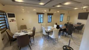 a dining room with tables and chairs and windows at Majesty Apartment in Asaba