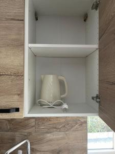 a cupboard with a jug and a vase in it at Maison f3 climatisée in Montceau-les-Mines