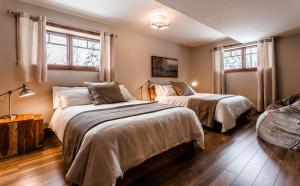 a bedroom with two beds and two windows at Chalet Le Mont-Blanc in Saint-Faustin