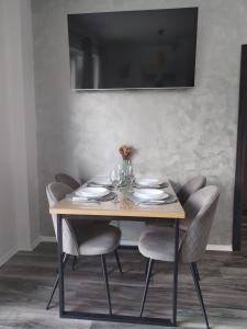 a dining room table with chairs and a television on the wall at Apartment Ćulum in Peračko Blato